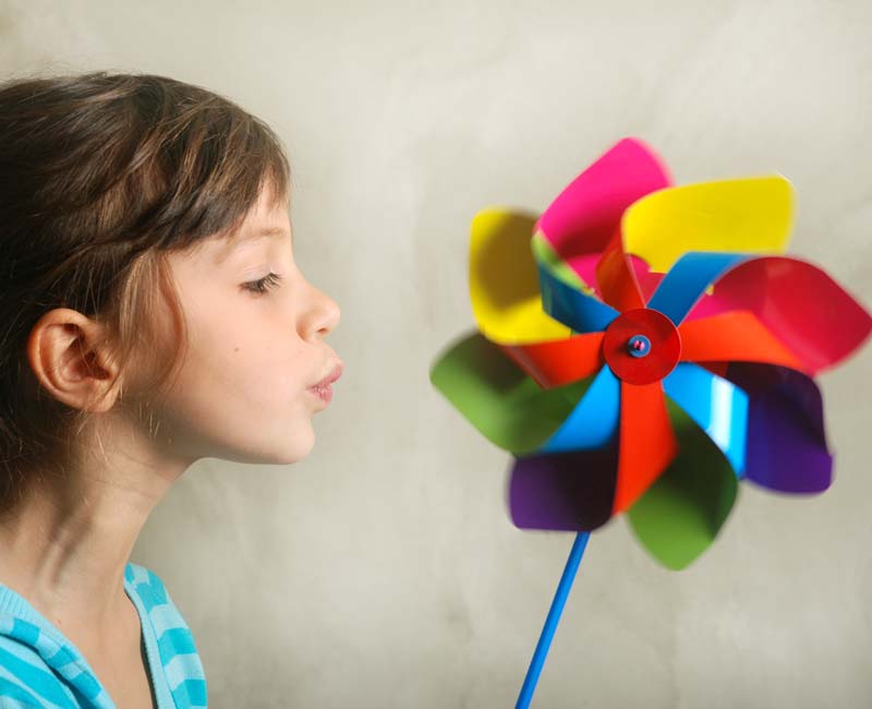 Child blowing on a spin wheel.