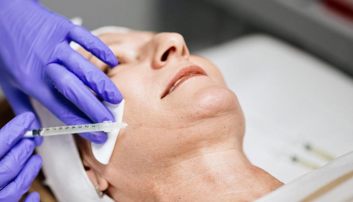 A healthcare provider injecting a jawline filler into a person’s facial skin.