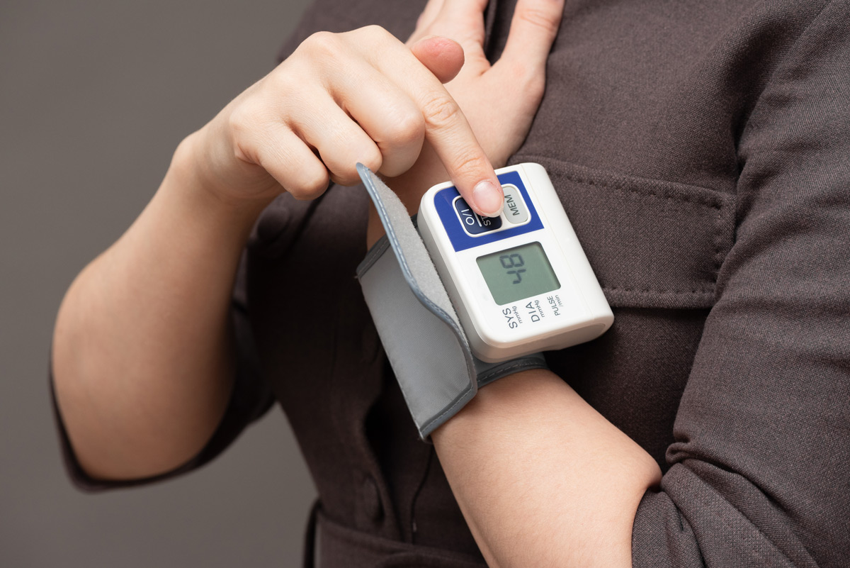 Photo of someone using a wrist blood pressure monitor.