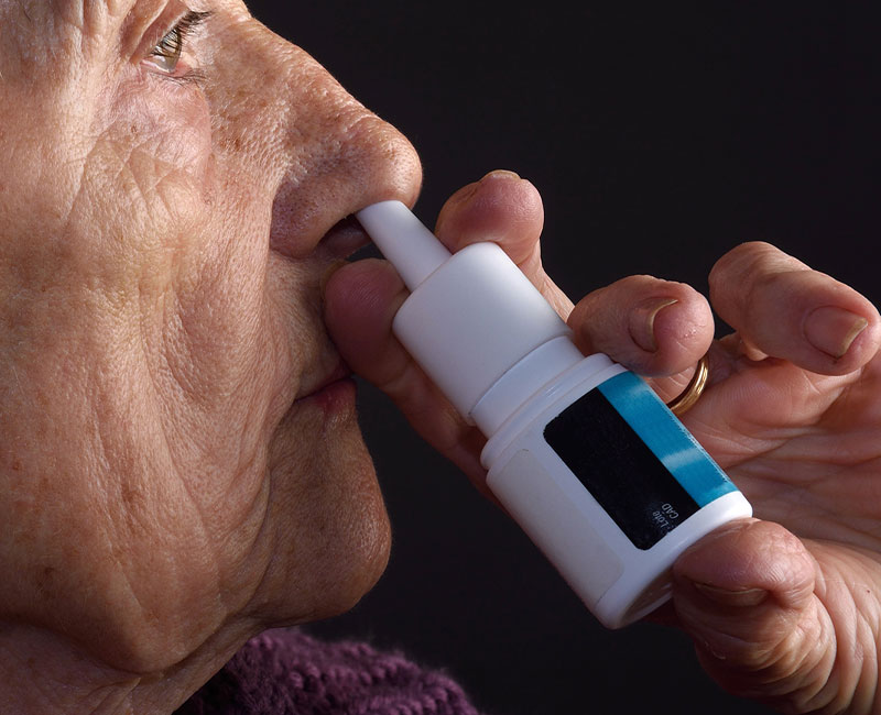 A person uses a nasal spray to relieve their stuffy nose (nasal congestion).