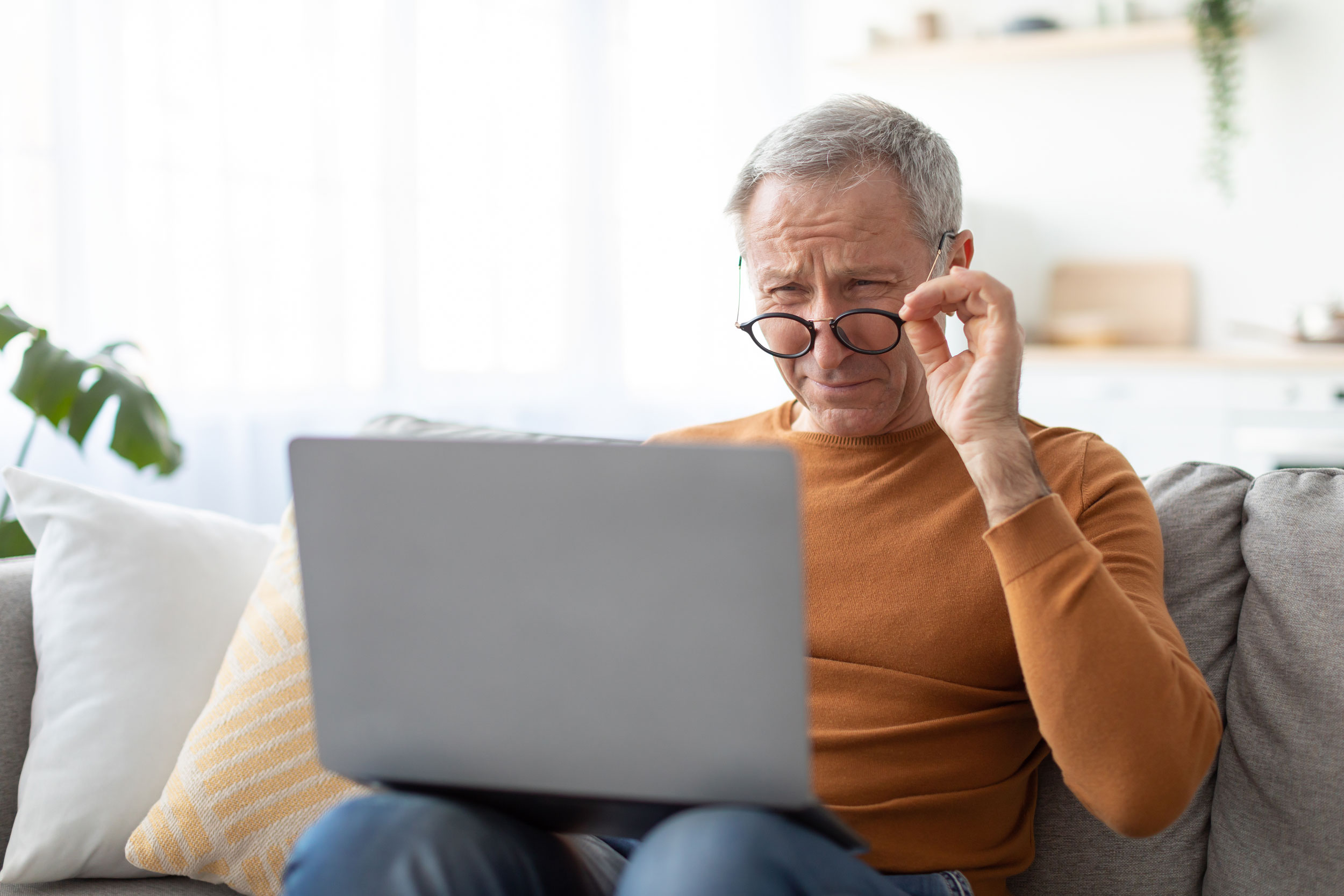 Photo of a person lowering their glasses and squinting to see a computer screen up-close.