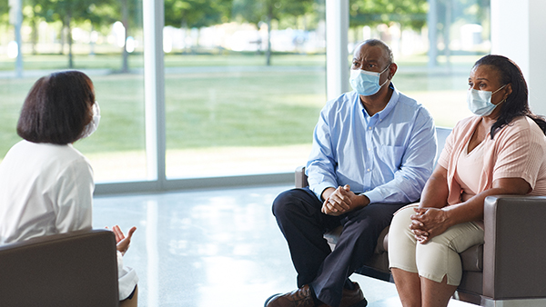 Husband and wife talking to Cleveland Clinic doctor in masks