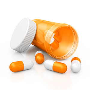 A round container of medication with pills on the counter.