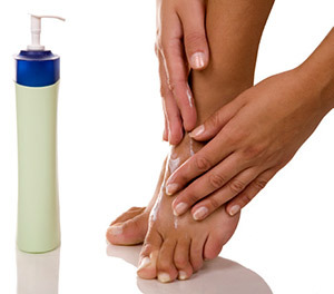 A woman rubbing lotion on her feet.