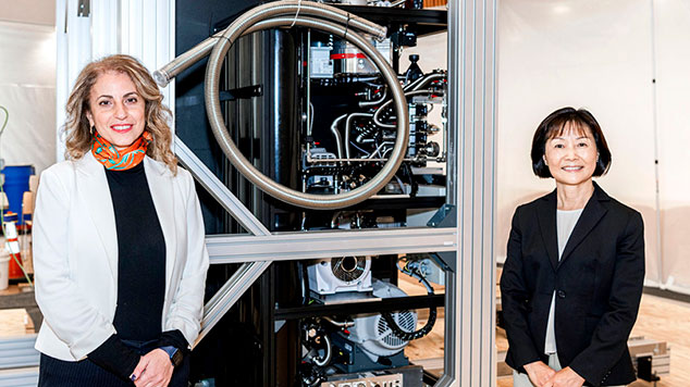 Lara Jehi, M.D. and Ruoyi Zhou, Ph.D. stand in front of a machine at the site of the IBM Quantum System One.