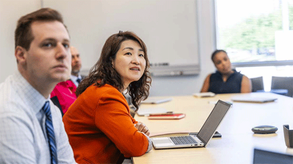 Group of healthcare professionals converse during a workplace visit or meeting.