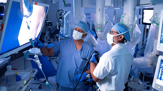 Surgeons review live imaging on a monitor during a minimally invasive procedure in a high-tech operating room.