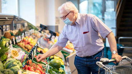 older man shopping in grocery store with mask
