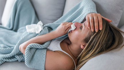 Woman blowing nose on couch