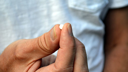 Person holding small white pill