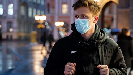 Young man standing outside in the dark with mask