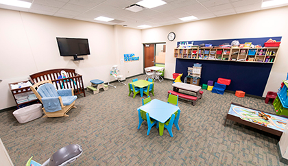 Kids playroom with a crib, toys, table and chairs