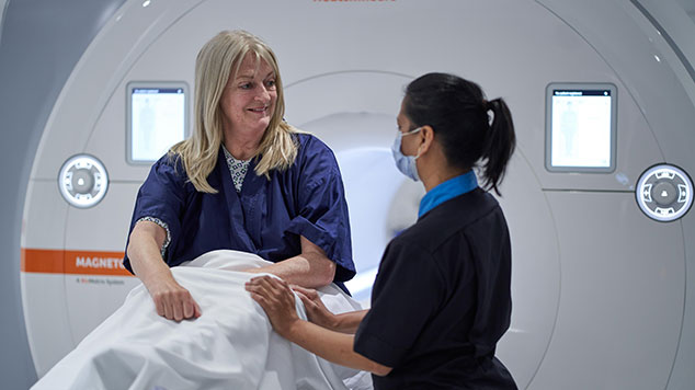 A patient talking to a caregiver outside of a computerized tomography (CT) scan device.