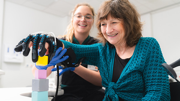 Patient with glove device on hand grabbing blocks.