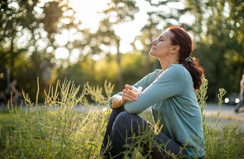 Woman sitting in the grass breathing in fresh air.