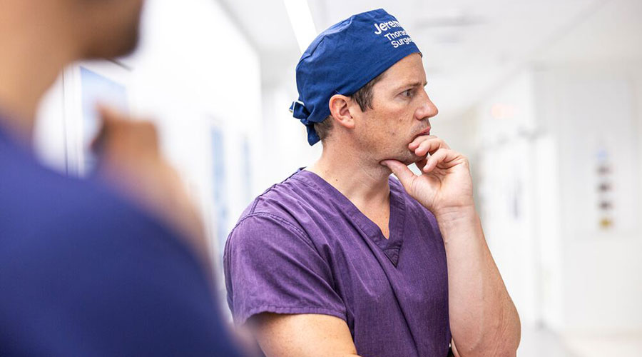 Doctor resting his hand on his chin with his arms crossed.