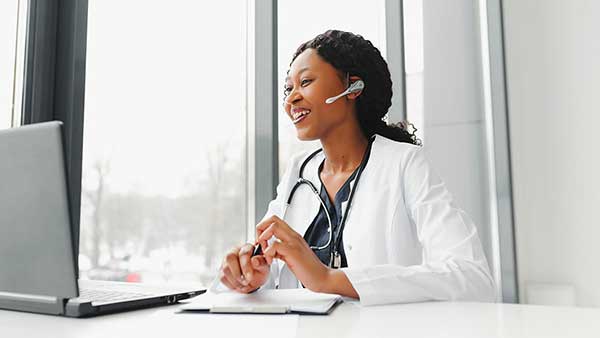 Physician wearing a whitecoat on a virtual call on a laptop computer.