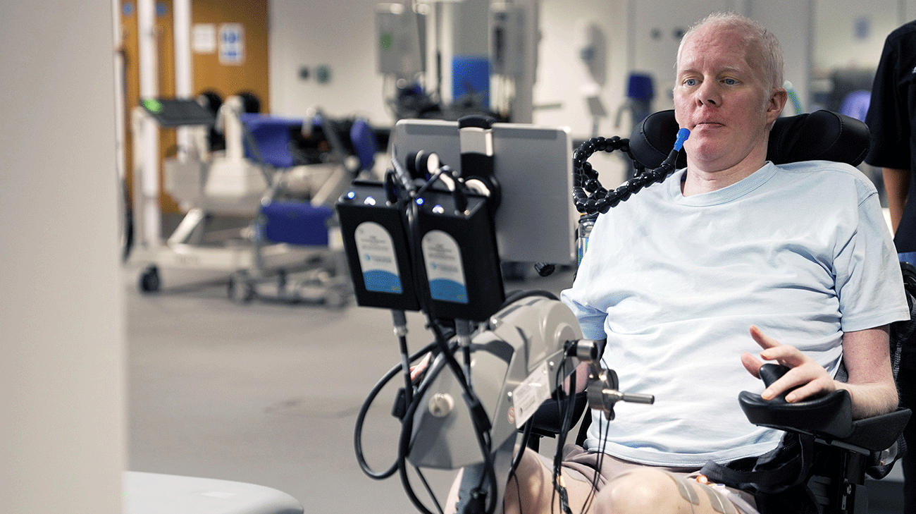 David Smith using a rehabilitation therapy bike while a Cleveland Clinic London physical therapist provides guidance.