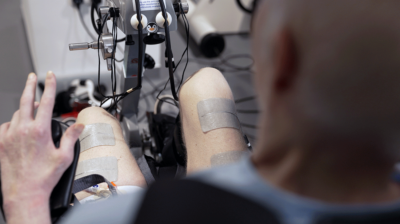 Close-up photo of a leg with electrical stimulation electrodes attached during rehabilitation therapy.