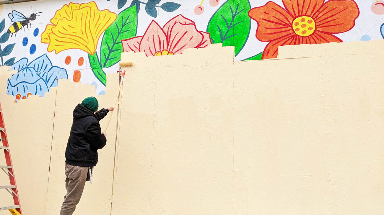 Jon Sedor painting a mural wearing a device to treat his glioblastoma. 