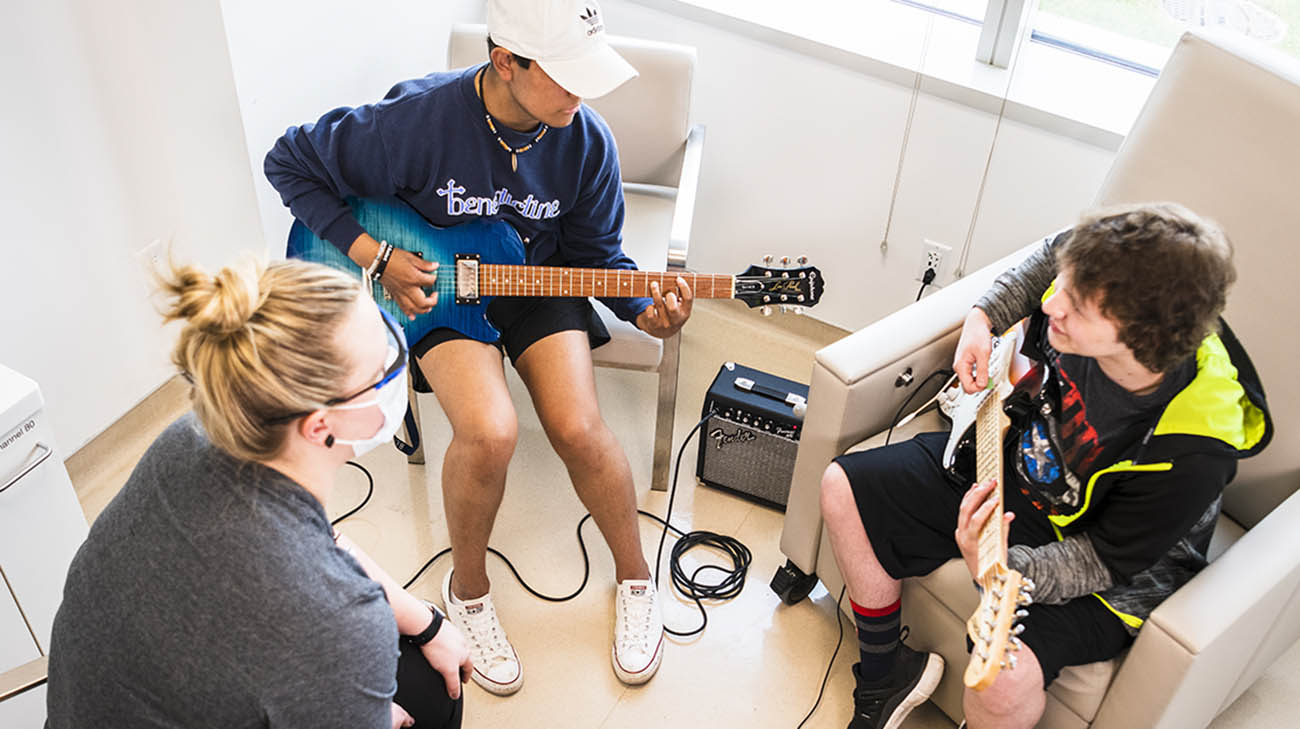 Teen cancer patients play guitar with Cleveland Clinic Children's music therapist. 