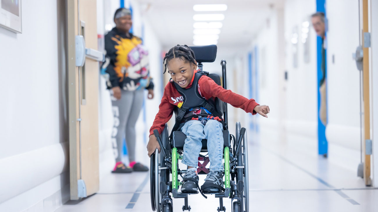 Patient, JaLontae Price, excitedly moves down the hospital corridor in his manual wheelchair.