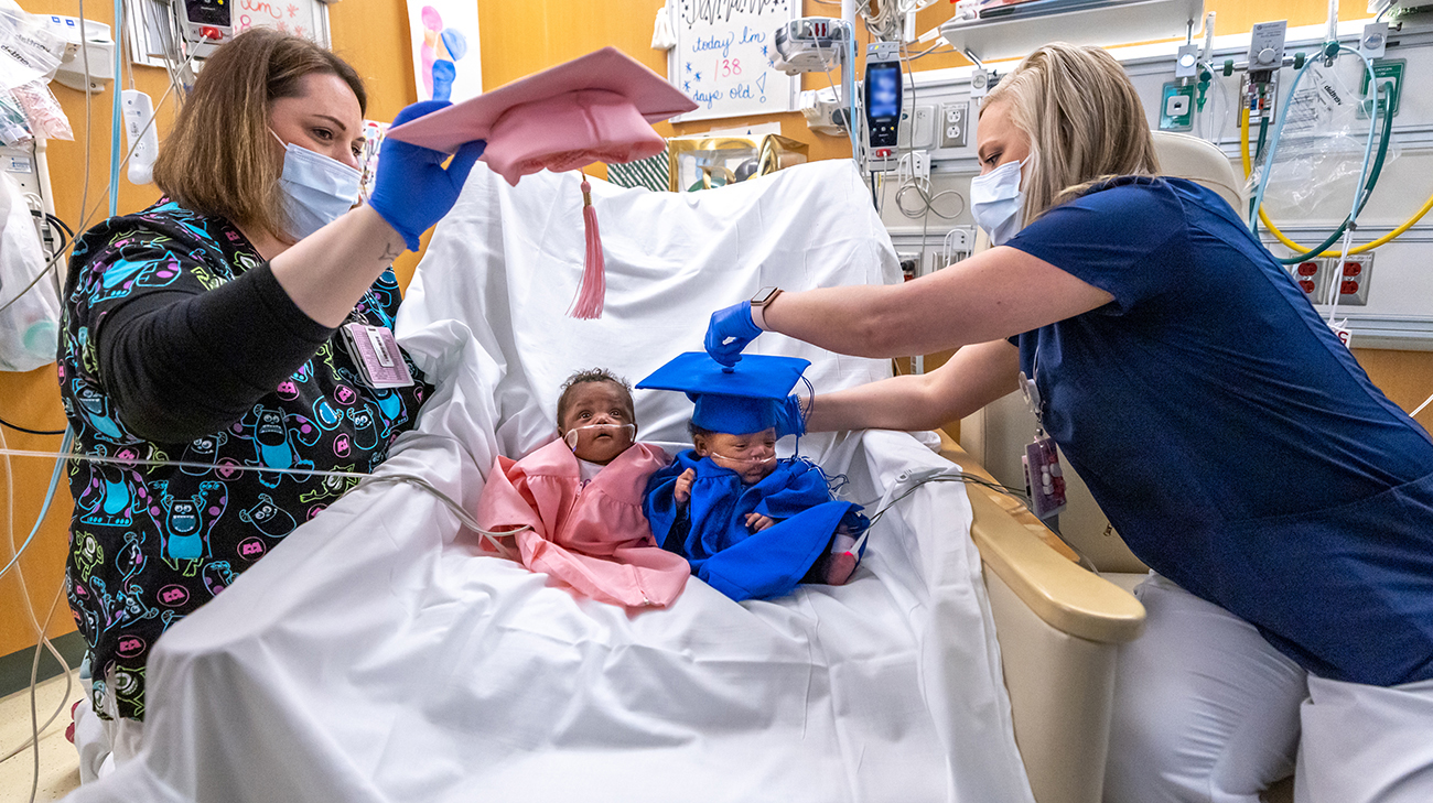 The twins wearing graduation caps and gowns on they day they were released from the hospital.