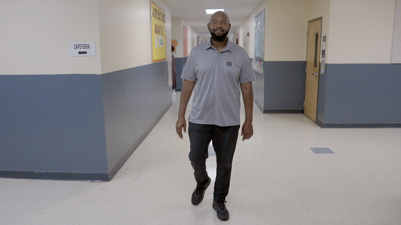 Harold Pearson walking down the hallway of a high school.