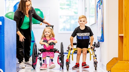 Aaron and Stephanie Levandusky using mobility walkers to move down the hospital hallway.