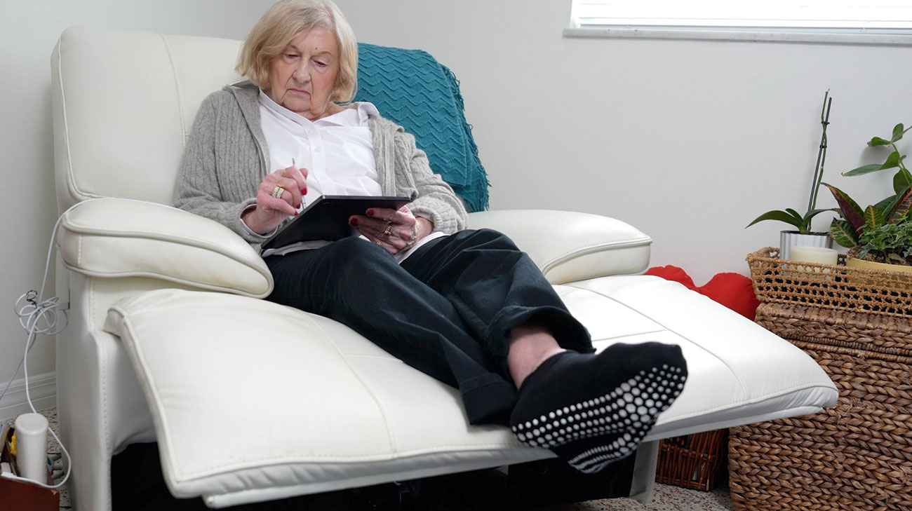 Diane Fiedler sitting on a pullout chair while journaling.