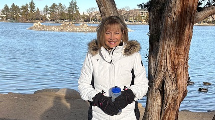 Patient, Diane Hartman, pictured outdoors in front of a lake.