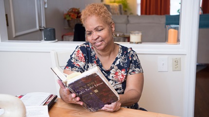 Cheryl West reading a book in her kitchen