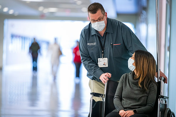 Cleveland Clinic caregiver helping transport a patient outside the hospital.