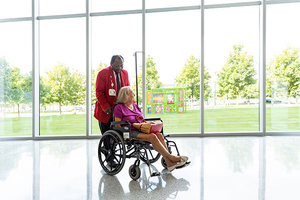 Cleveland Clinic caregiver helping transport a patient outside the hospital.