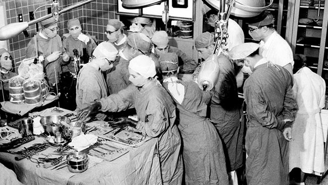 As observers look on, Cleveland Clinic surgeons Donald Effler, MD, and Larry Groves, MD, perform a stopped-heart operation in 1956 using the heart-lung bypass machine developed by Willem Kolff, MD, PhD.
