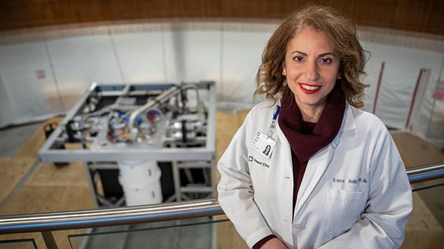 Portrait of Dr. Lara Jehi with IBM Quantum System One in the background.