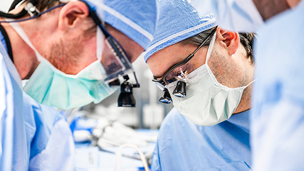 Two Cleveland Clinic doctors in surgery looking down at patient.