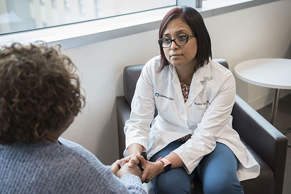 Cleveland Clinic doctor sitting down and talking with patient in examination room.