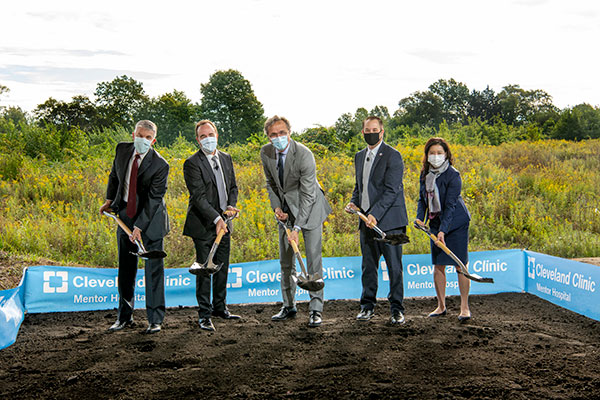 Five people with shovels breaking ground