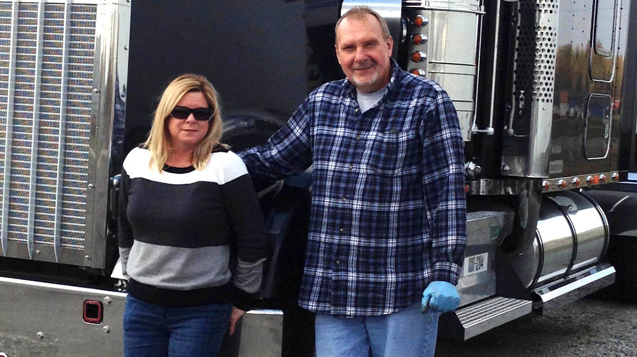 Keith Medovich with his wife, Brigitte, in front of one of the trucks he drives for work. 